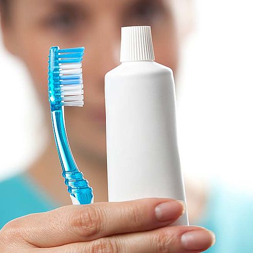 Woman holding a toothbrush and toothpaste in her hand